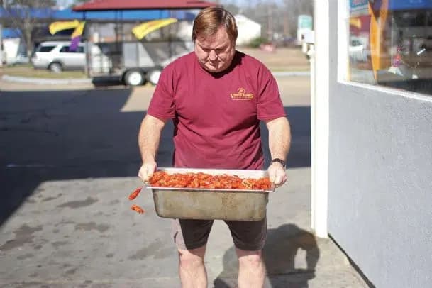 Curt Crissey carrying a fresh tray of crawfish outside Rosey Baby